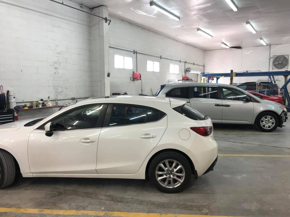 Two white cars are parked in a garage next to each other.