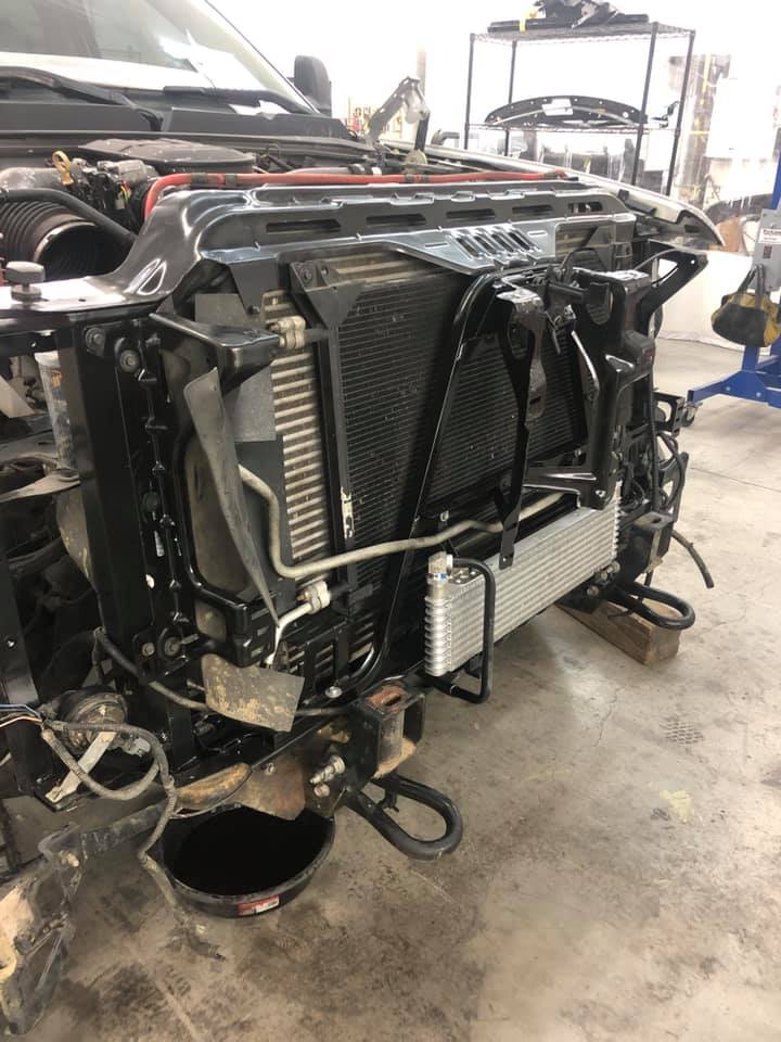 A car with the radiator removed is sitting in a garage.