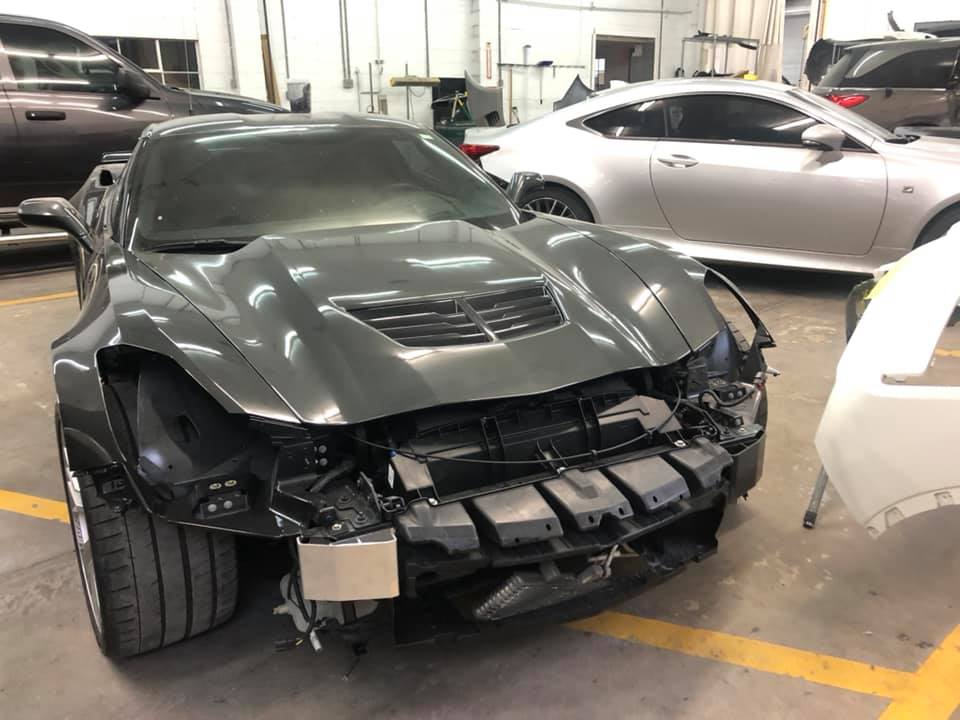 A damaged car is sitting in a garage next to other cars.