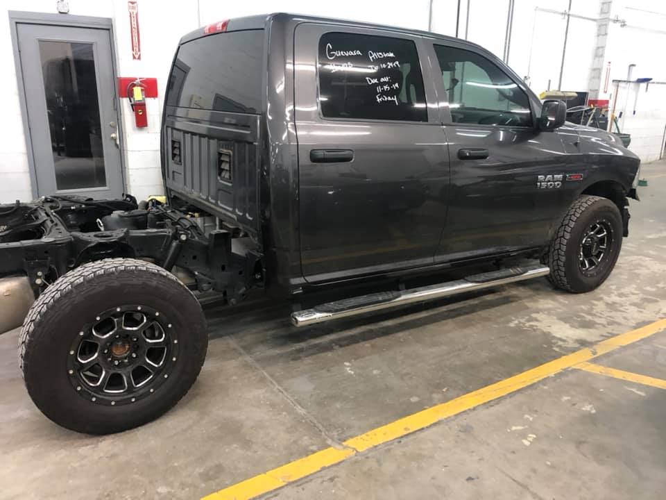 A ram truck is sitting in a garage with the bed removed.