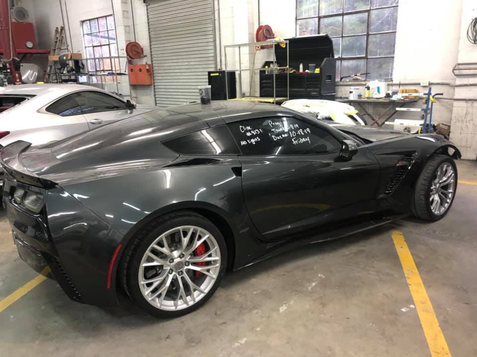 A black sports car is parked in a garage next to a white car.