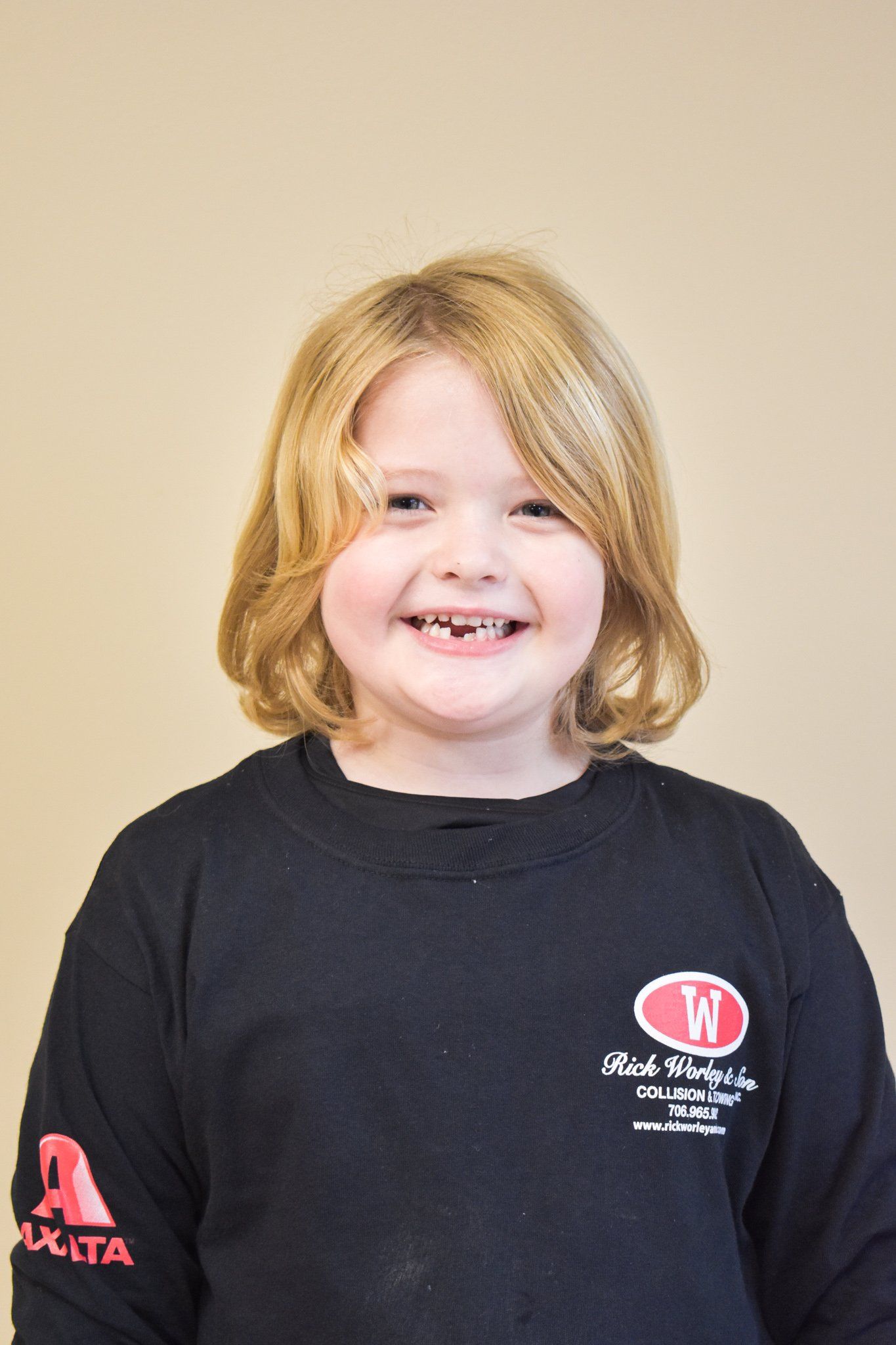A young girl wearing a black shirt is smiling for the camera.