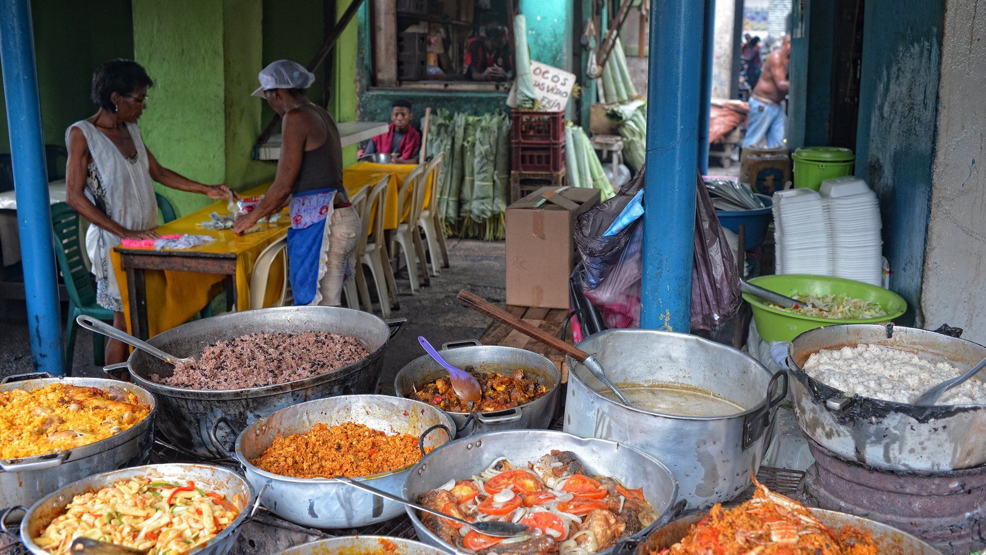 A woman is standing in front of a table filled with pots of food.