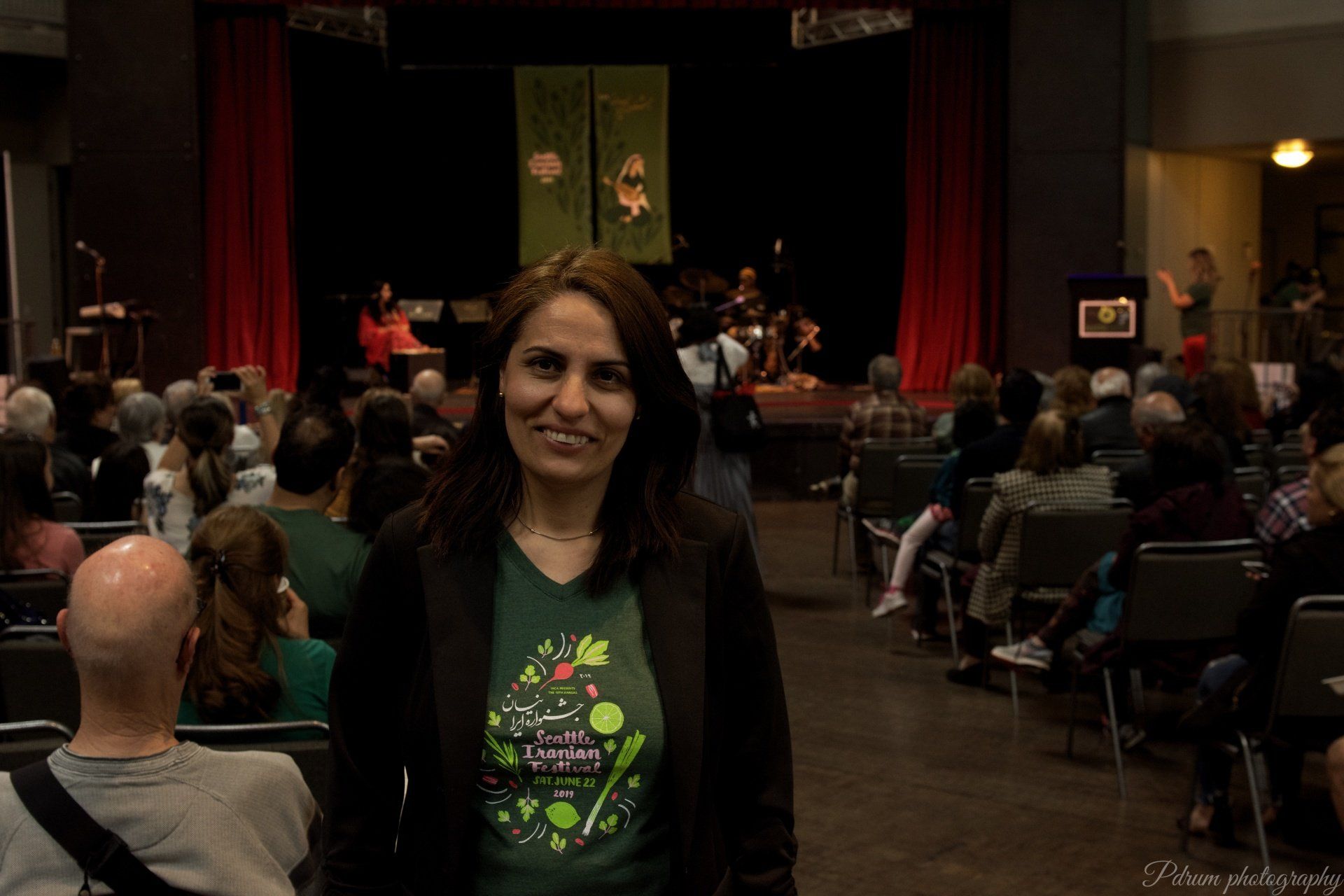 A woman is standing in front of a crowd of people in a theater.