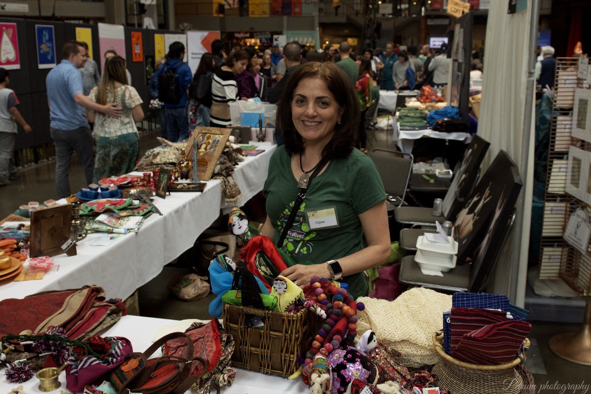 A woman in a green shirt is standing in front of a table full of items.