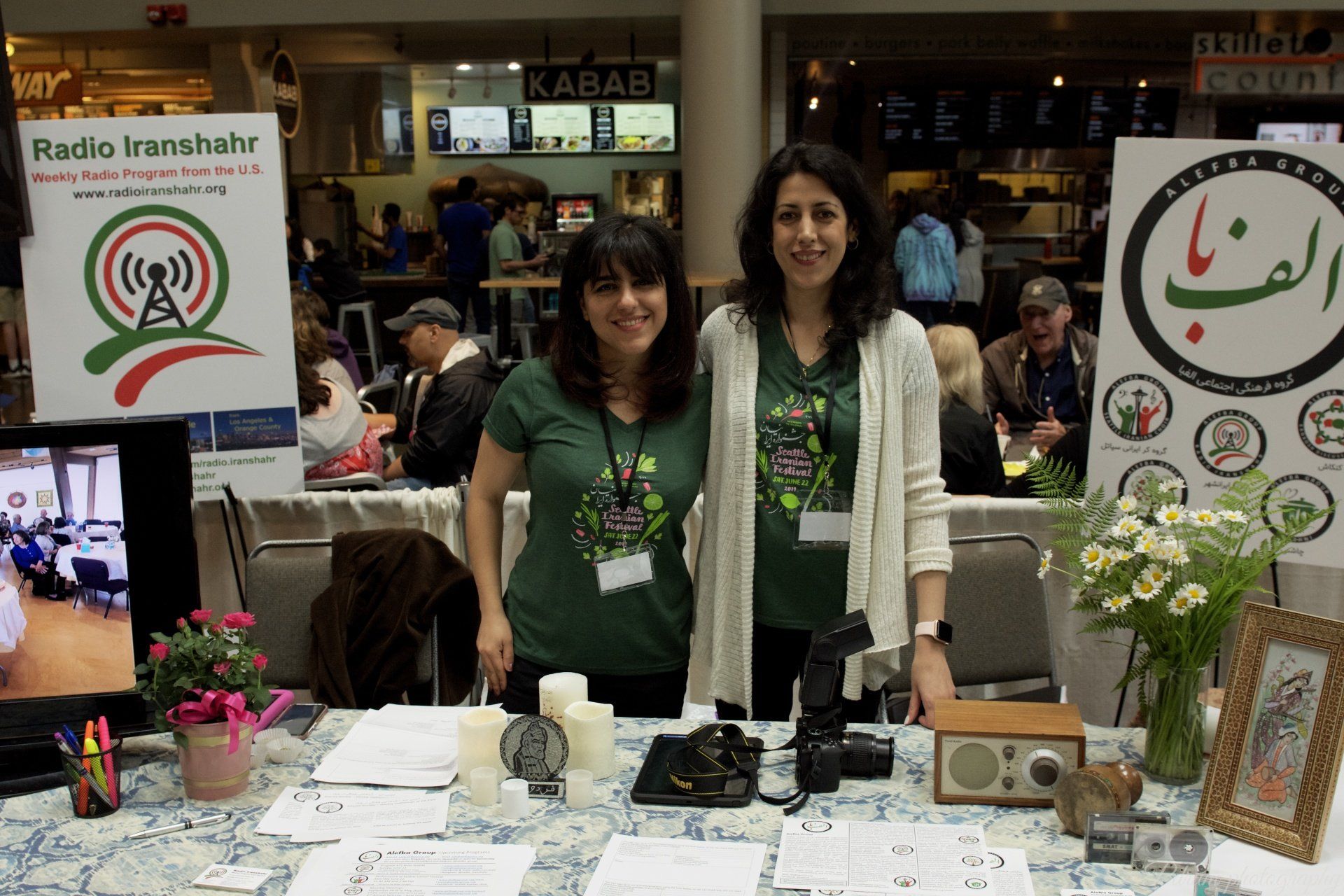 Two women standing in front of a table with a sign that says radio kashmir