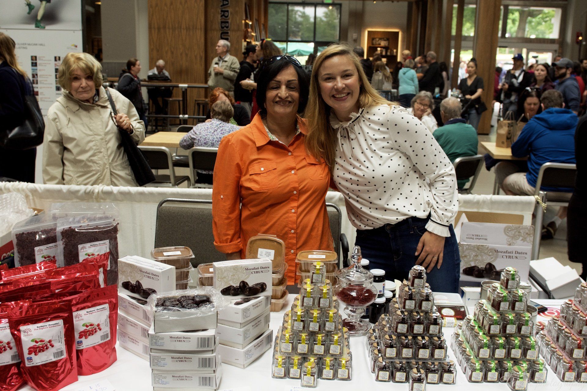 Two women are posing for a picture in front of a table full of chocolates.