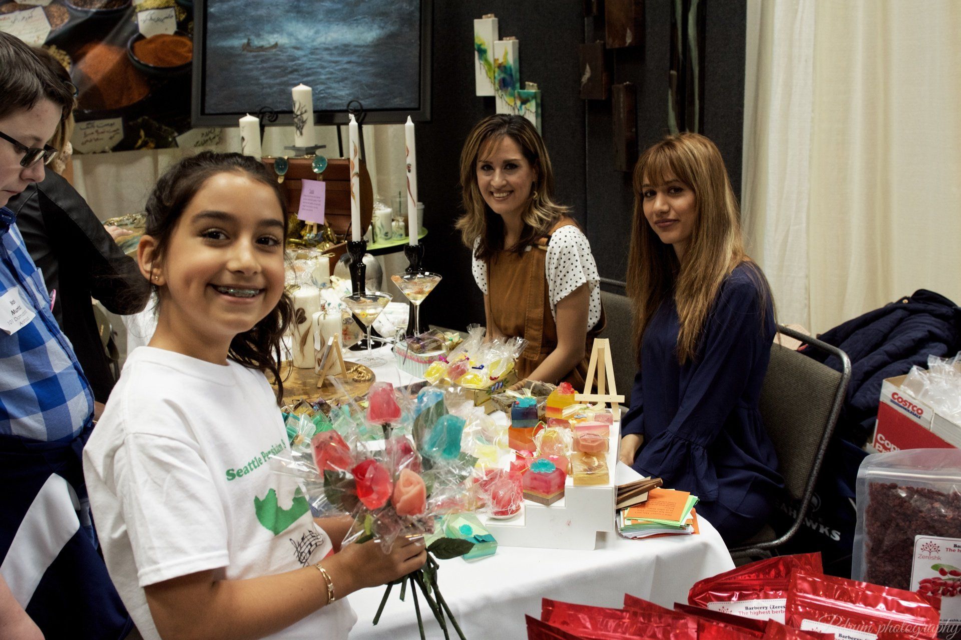 A girl is holding a bouquet of flowers while sitting at a table with other people.
