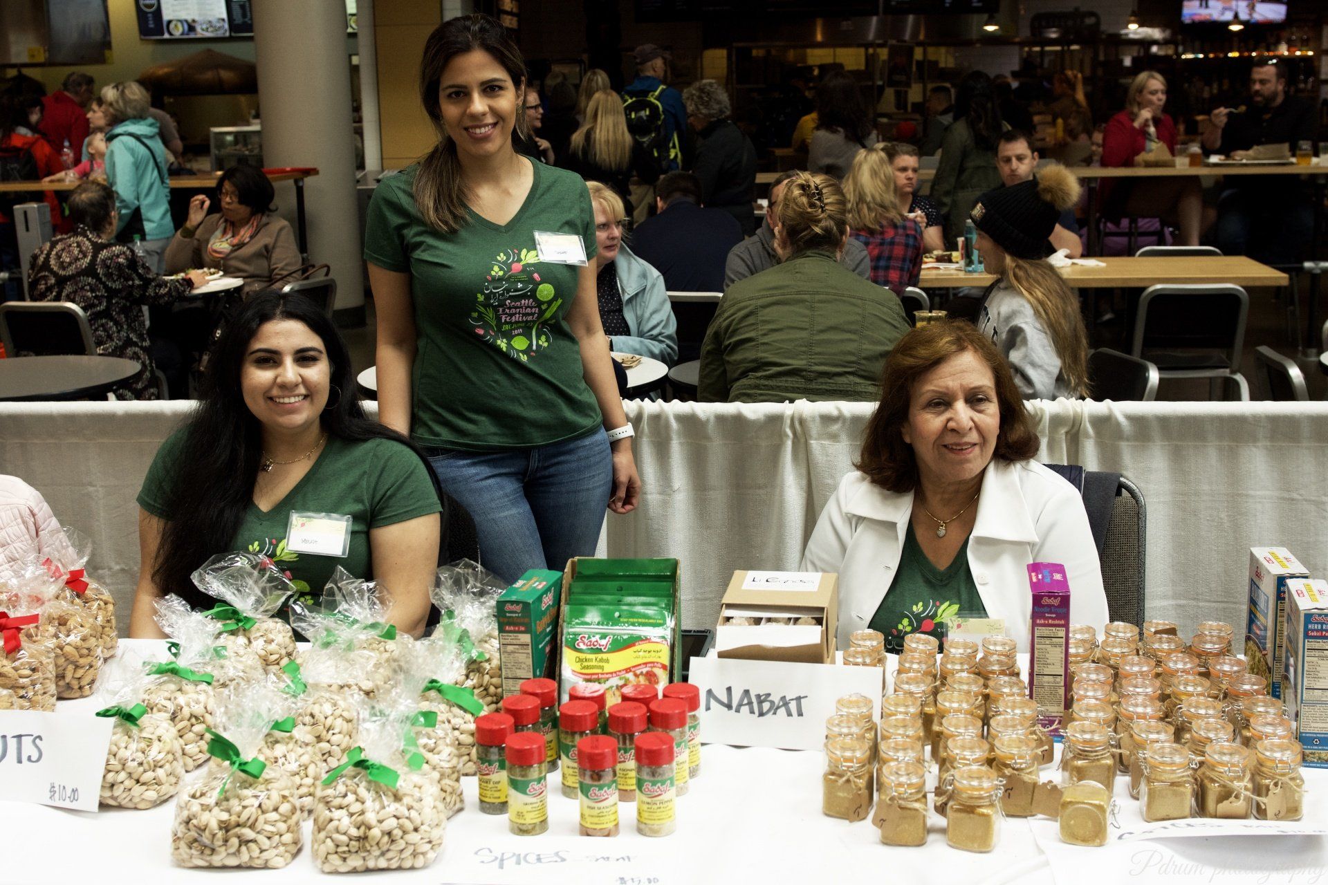 Three women are standing in front of a table with nuts on it