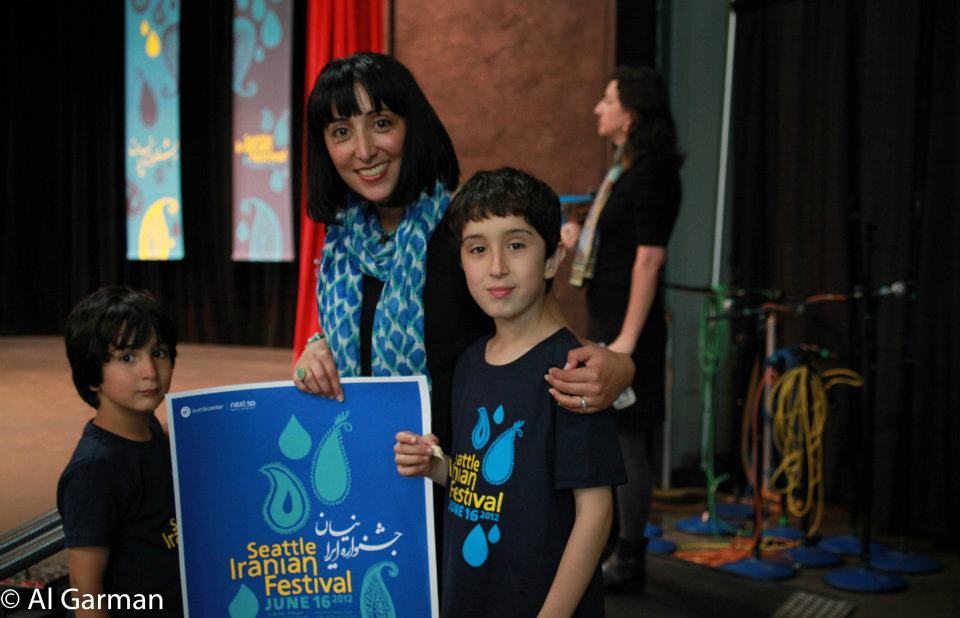 A woman holding a poster that says seattle iranian festival