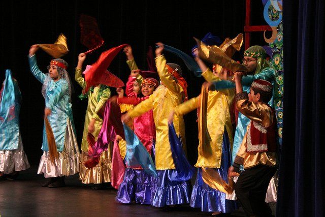 A group of people in colorful costumes are dancing on a stage.