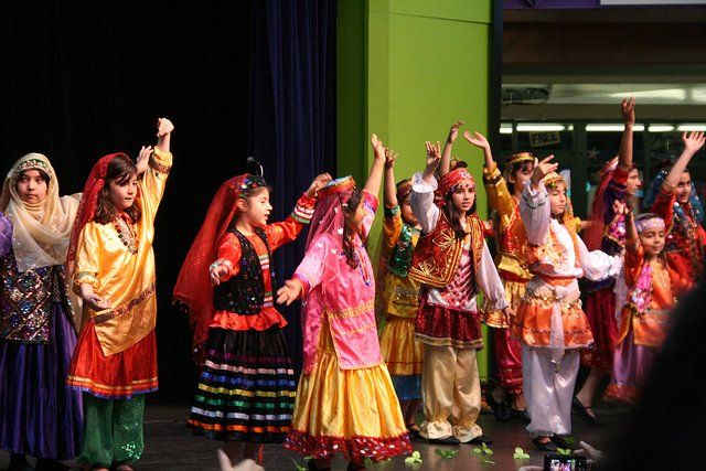 A group of children in traditional costumes are dancing on a stage.
