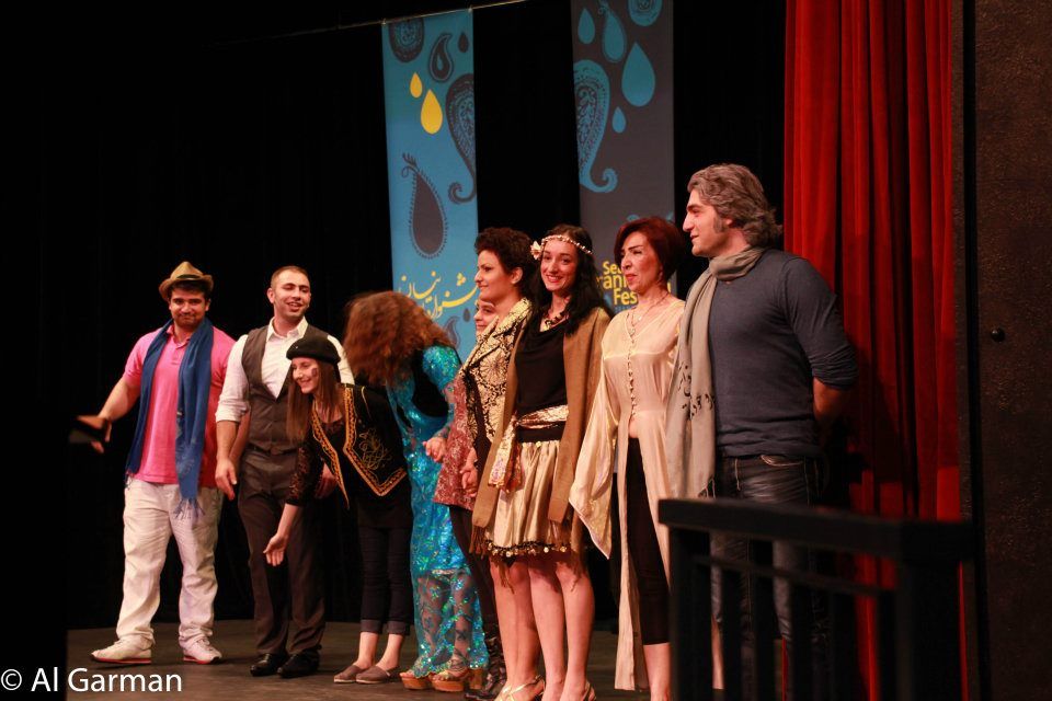 A group of people standing on a stage with a red curtain behind them
