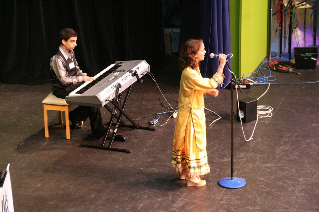 A man is playing a keyboard while a woman sings into a microphone
