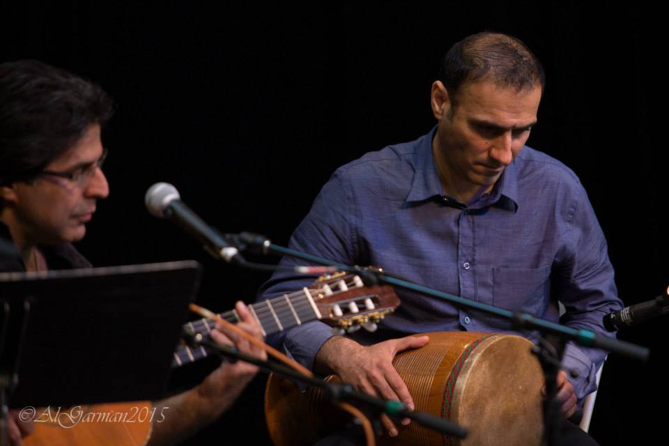 Two men are playing guitars and drums on a stage.