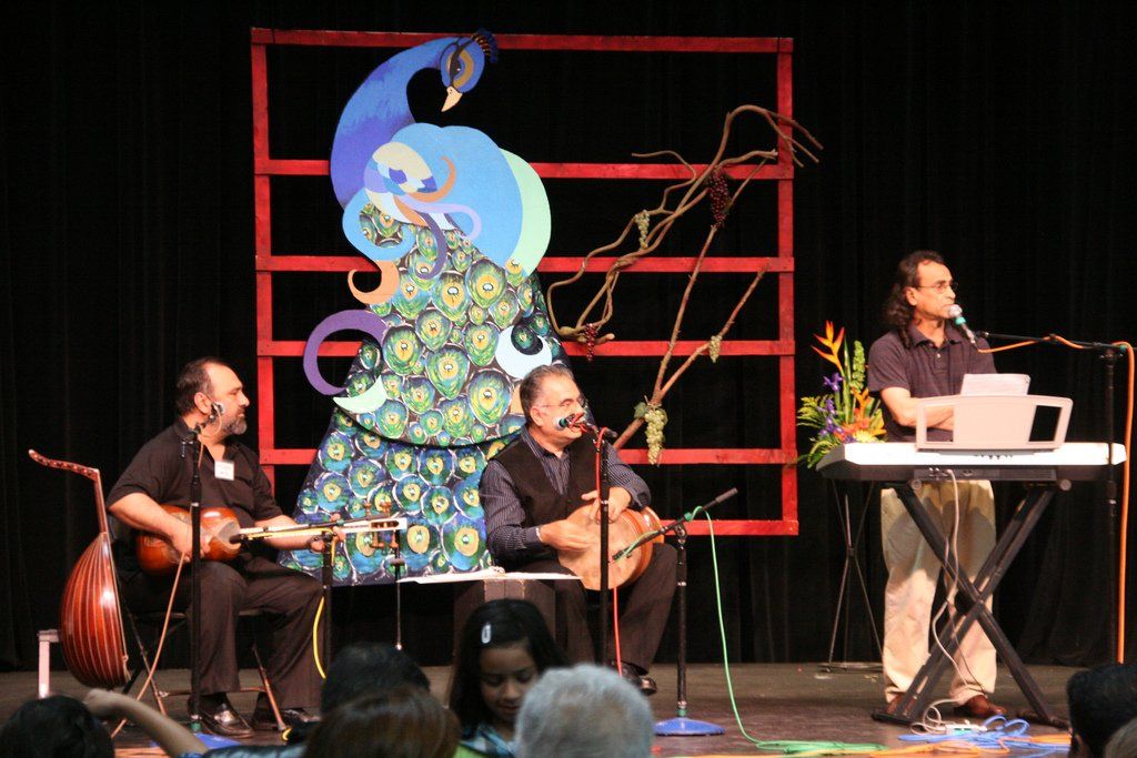 A group of men are playing instruments on a stage with a peacock in the background