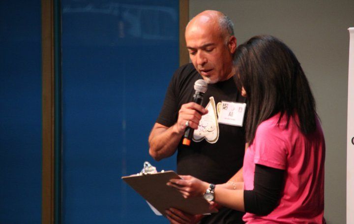 A man is holding a microphone while a woman holds a clipboard