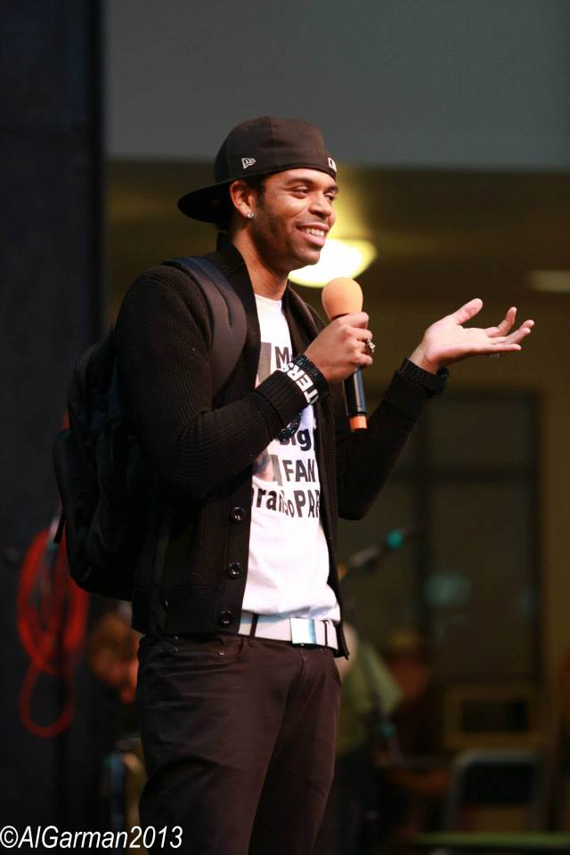 A man with a backpack is speaking into a microphone