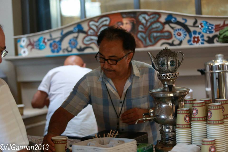 A man standing in front of a counter with cups and a teapot