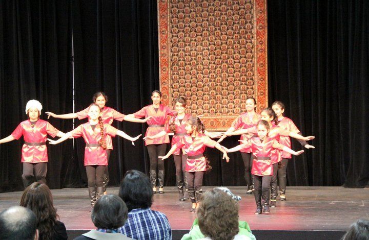 A group of people are dancing on a stage in front of a crowd