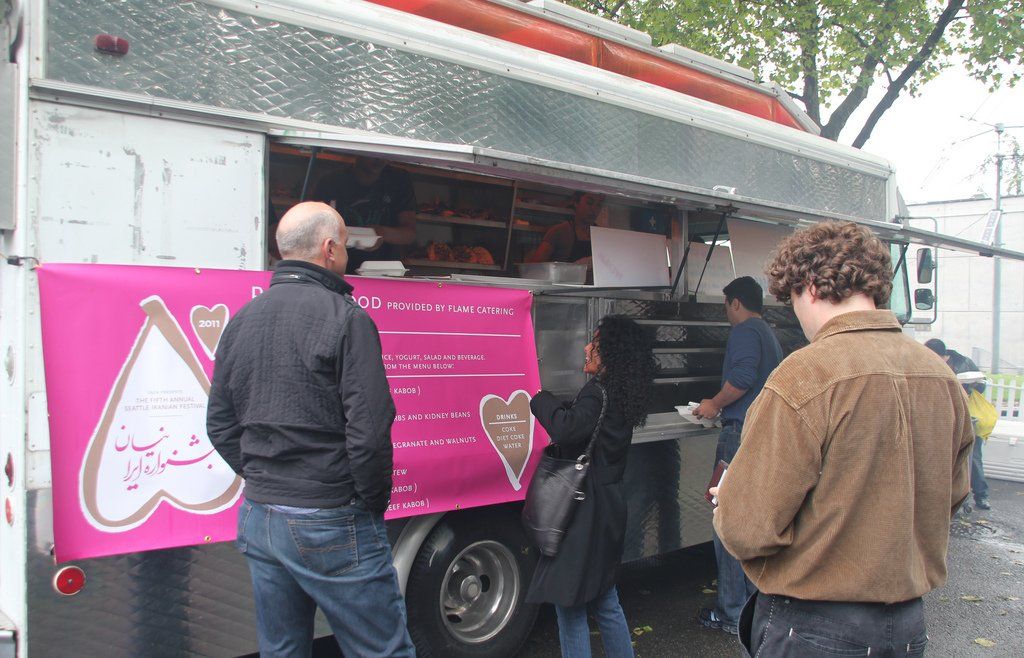 A group of people standing in front of a food truck