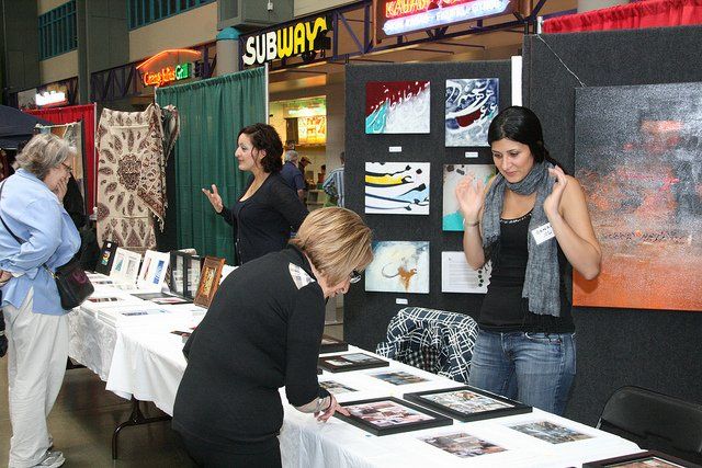 A group of women are looking at paintings in front of a subway sign