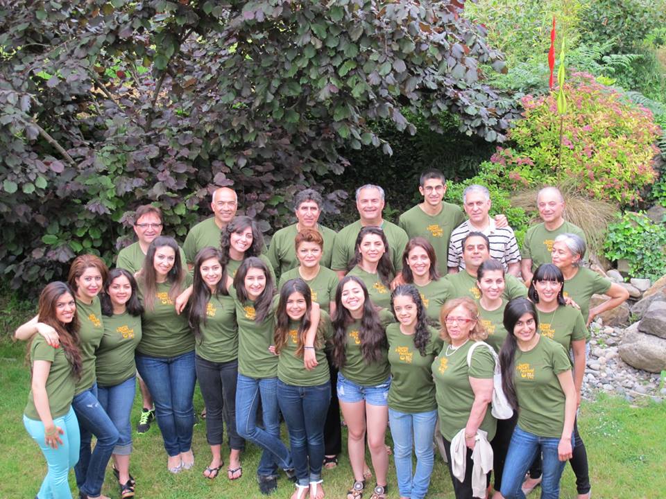 A group of people wearing green shirts are posing for a picture.