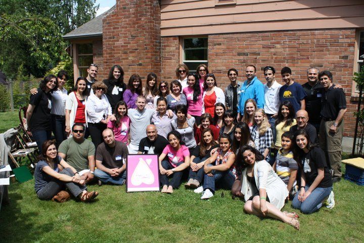 A group of people posing for a picture in front of a brick house