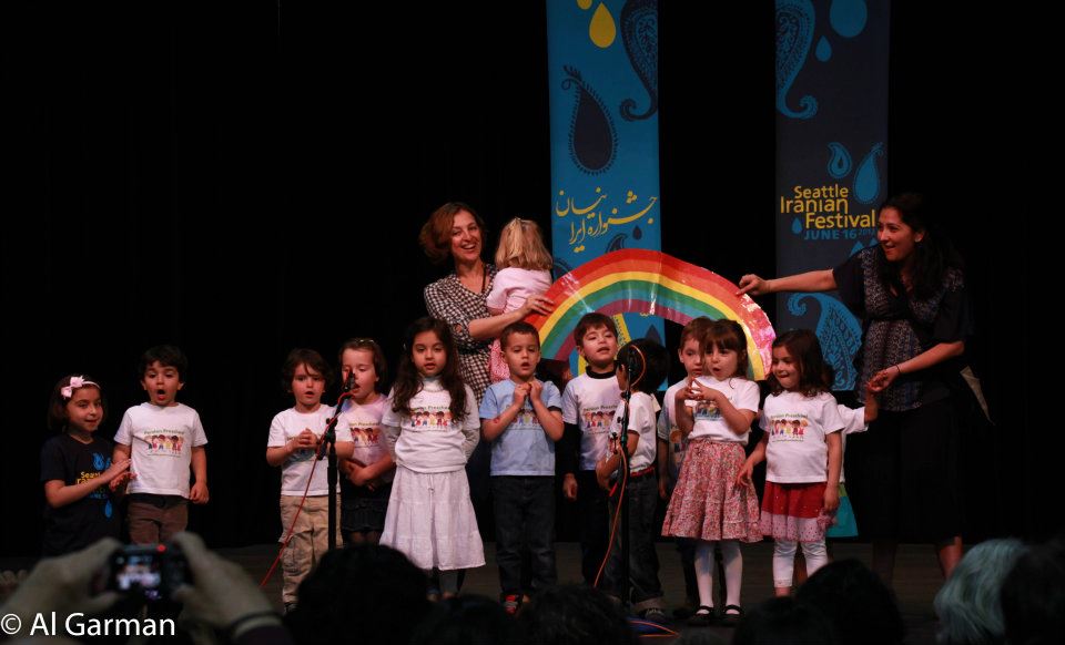 A group of children standing on a stage holding a rainbow