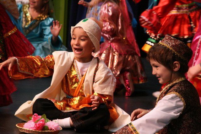 A group of children dressed in costumes are sitting on the floor