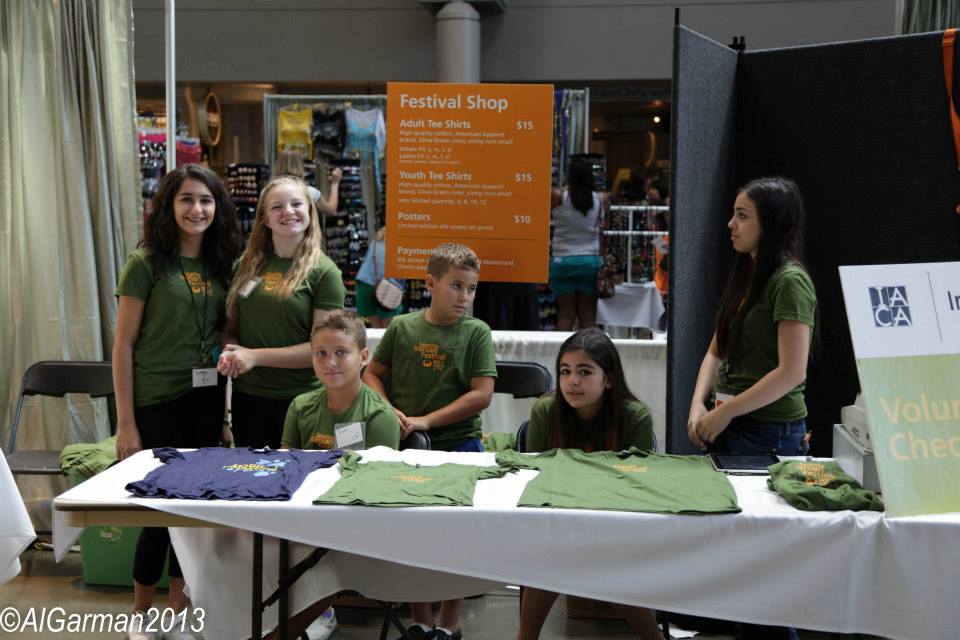 A group of people standing around a table with shirts on it