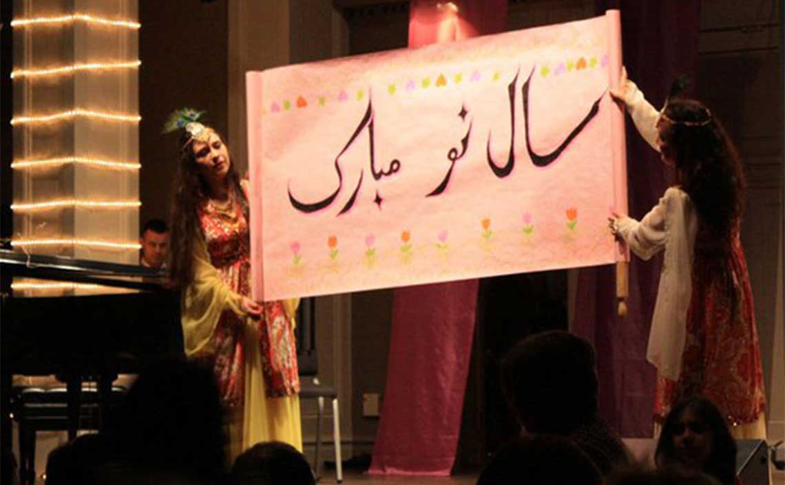 Two women are holding a sign with arabic writing on it