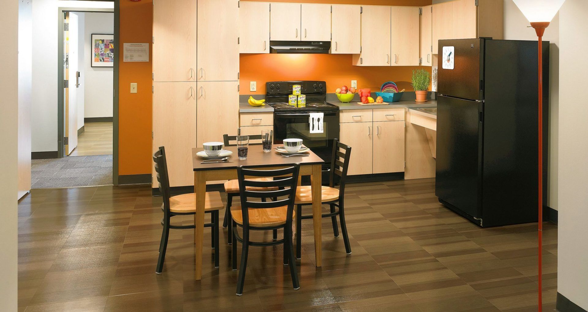 Modern kitchen with dark brown tile flooring, light wood cabinets, black appliances,