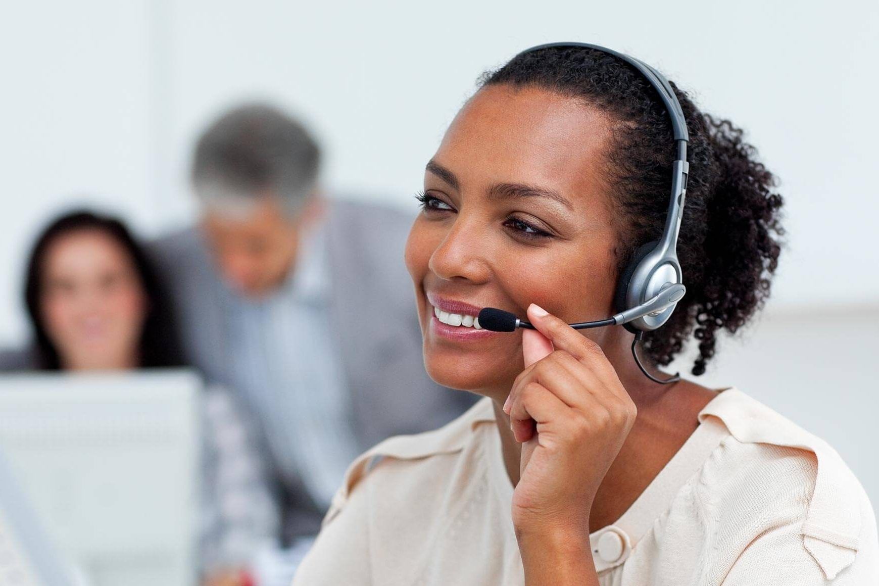 A woman wearing a headset is smiling in a call center.