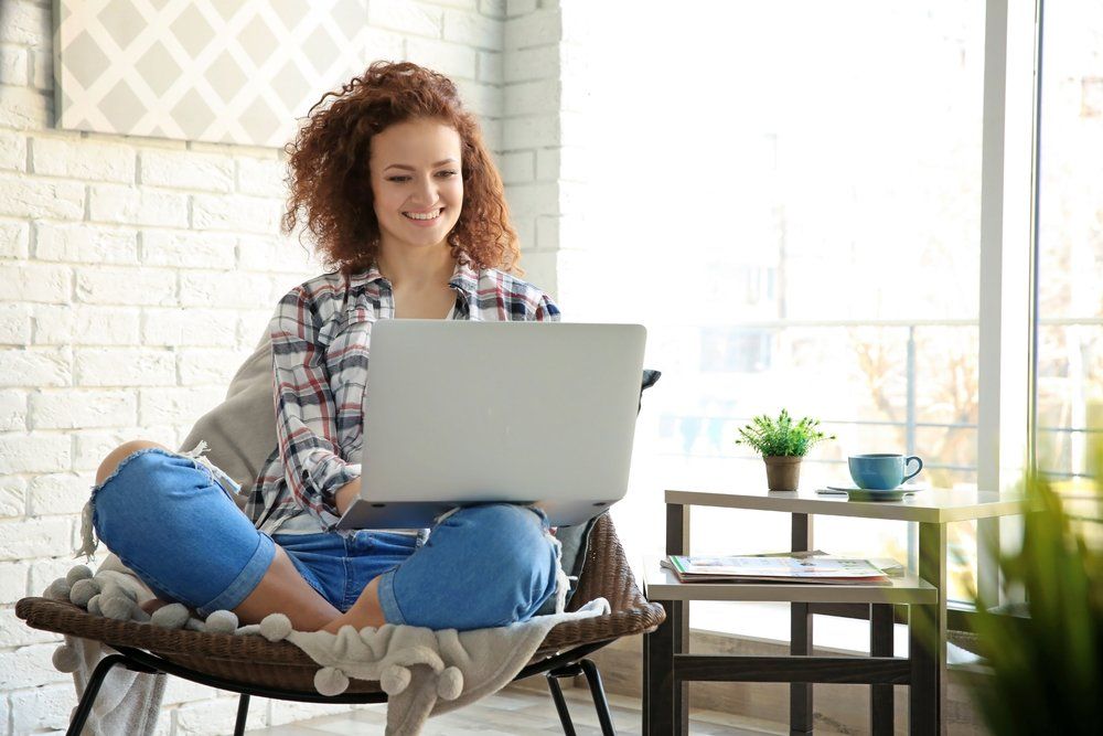 A woman is sitting in a chair using a laptop computer.