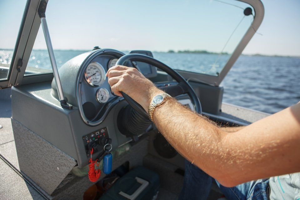 Una persona guida un motoscafo in mare aperto, con la mano sul volante e l'orologio al polso.
