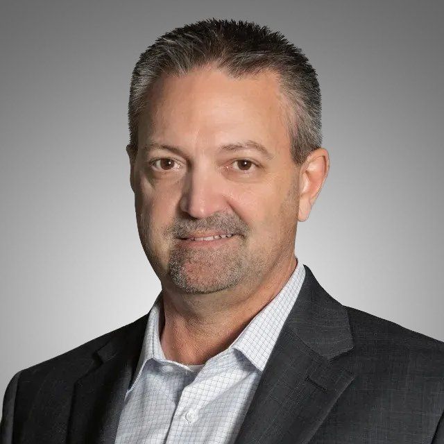 A man in a suit and white shirt is smiling for the camera.