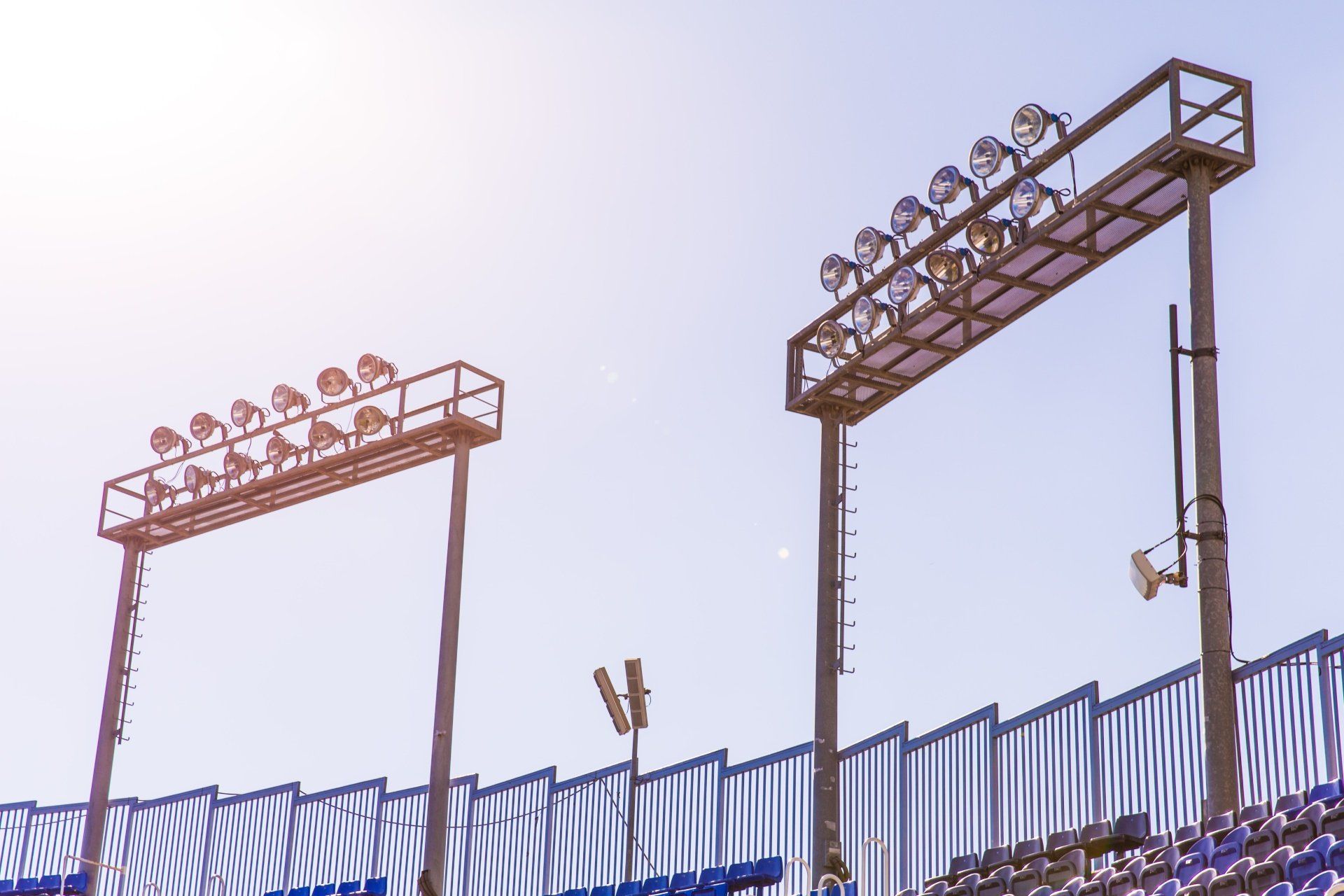 A stadium with a lot of lights on the stands and a blue railing.
