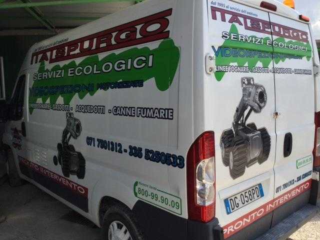 Furgone bianco di Ecologic Services con scritte verdi e rosse e grafica relativa a impianti idraulici/attrezzature parcheggiato all'aperto.