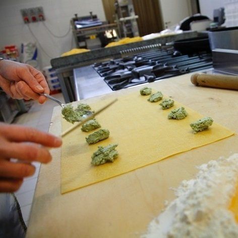 due mani di un uomo che preparano dei ravioli freschi