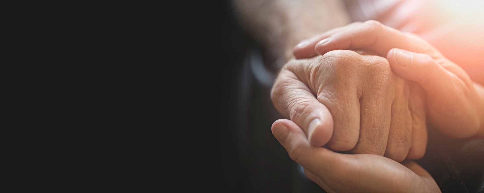A woman is holding the hand of an older woman.
