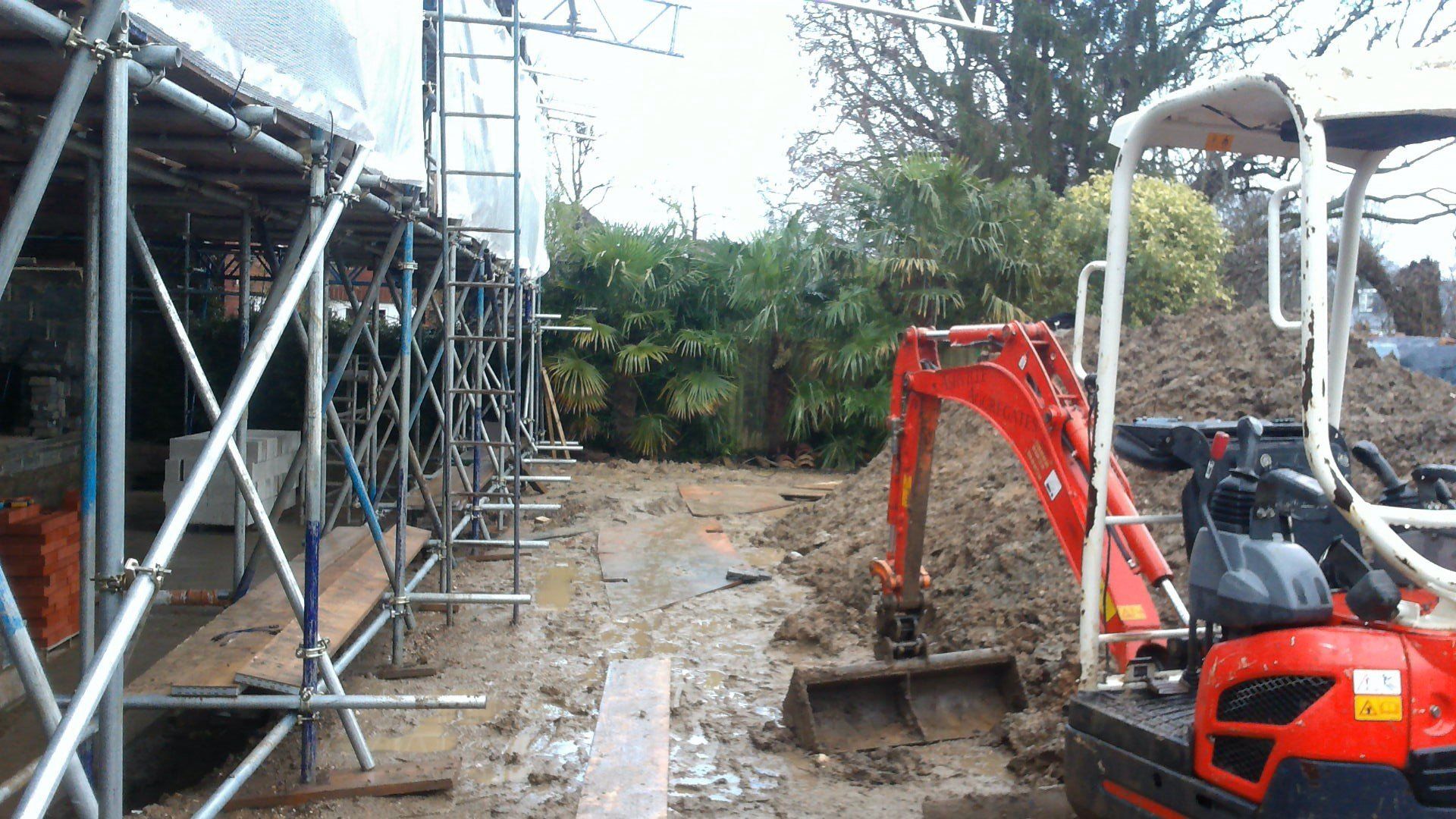 before A small red excavator is digging a hole in the dirt.
