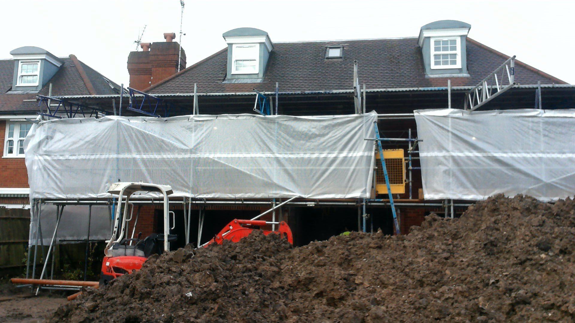 before A large pile of dirt is in front of a house under construction
