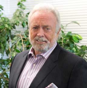A man with a beard is wearing a suit and striped shirt.