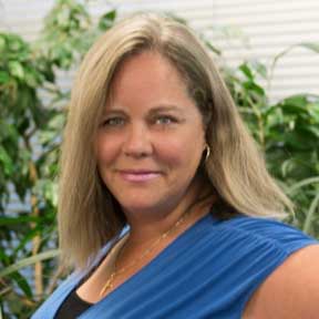 A woman in a blue shirt is smiling for the camera.