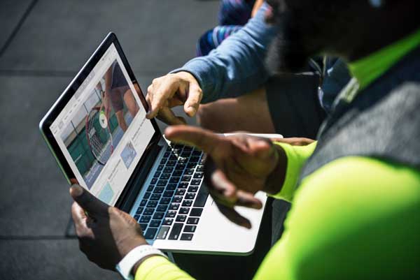 A man in a neon green shirt is using a laptop computer.