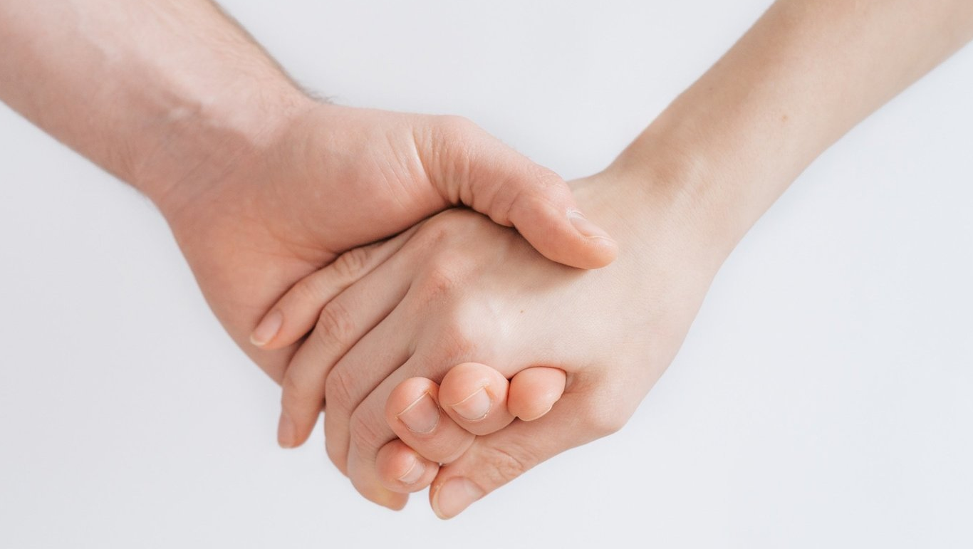 Two hands clasped together against a white background