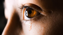 Close-up of a brown eye with a teardrop on the cheek