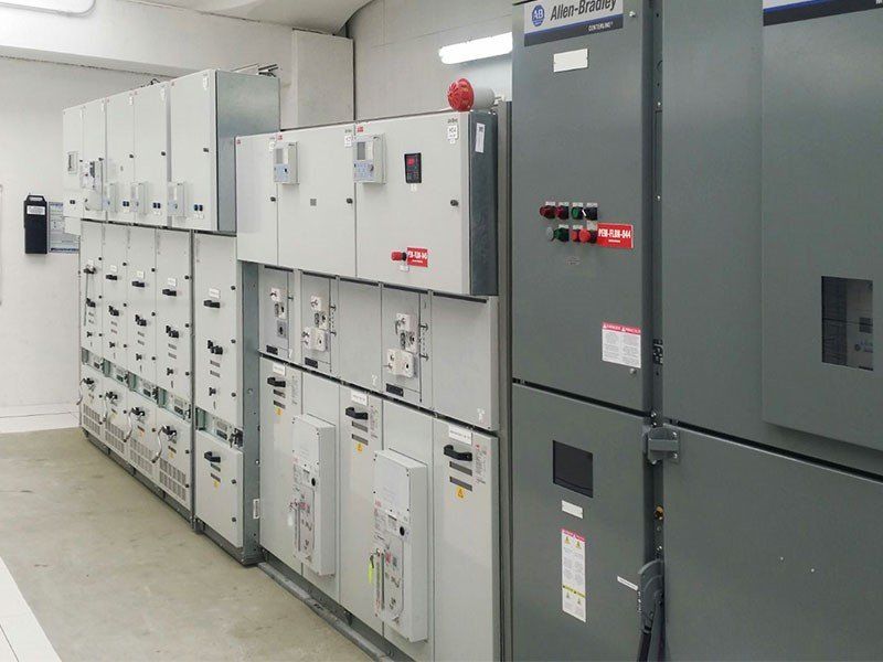 Apparecchiature elettriche di commutazione in un locale tecnico. Armadietti in metallo grigio con vari comandi e indicatori.