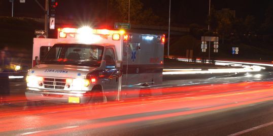 An ambulance is driving down a street at night.